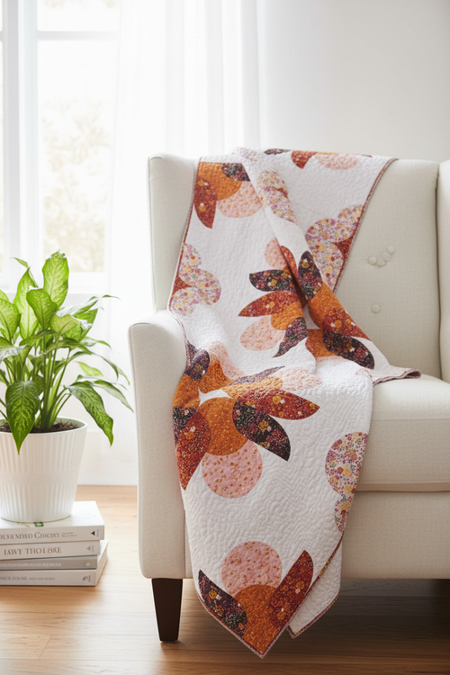 Big Island Blooms Quilt Pattern lifestyle photo — modern curved petal quilt draped over white linen armchair with tropical plant